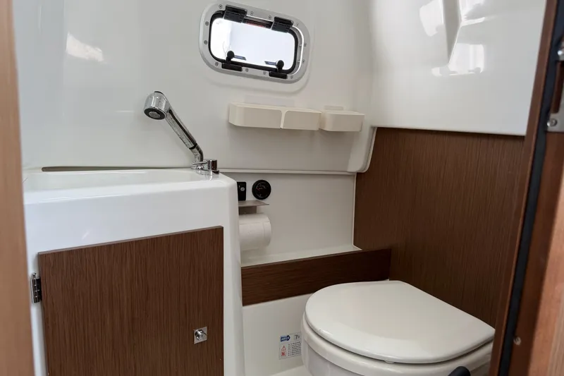 Slide: The Image of 2022 Jeanneau Leader 9.0 CC boat bathroom with sink, toilet, and porthole window. - 20