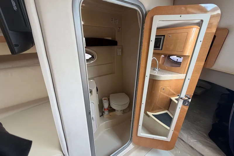 Slide: The Image of Interior of 2011 Four Winns V285 boat featuring bathroom and kitchenette area. - 83