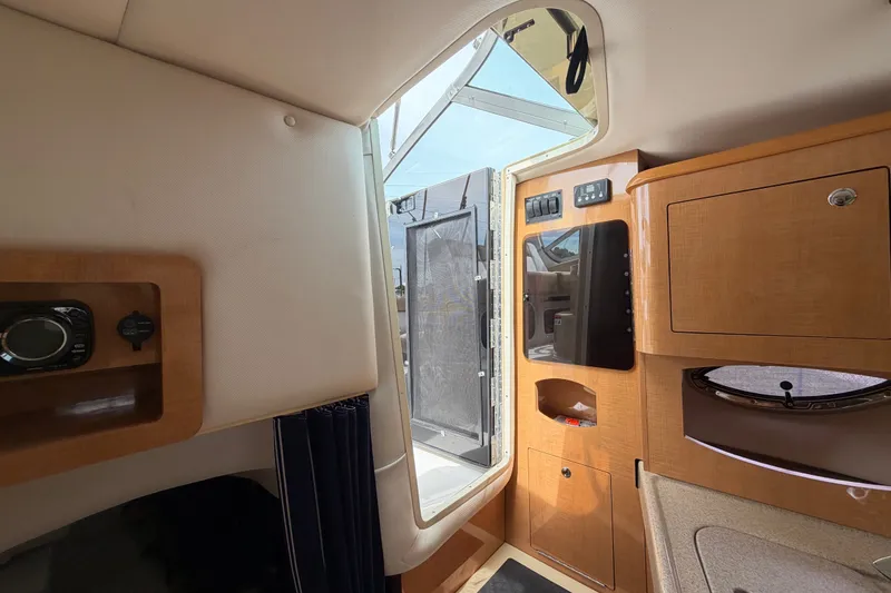 Slide: The Image of Interior view of 2011 Four Winns V285 boat cabin with wood cabinetry and open door. - 99