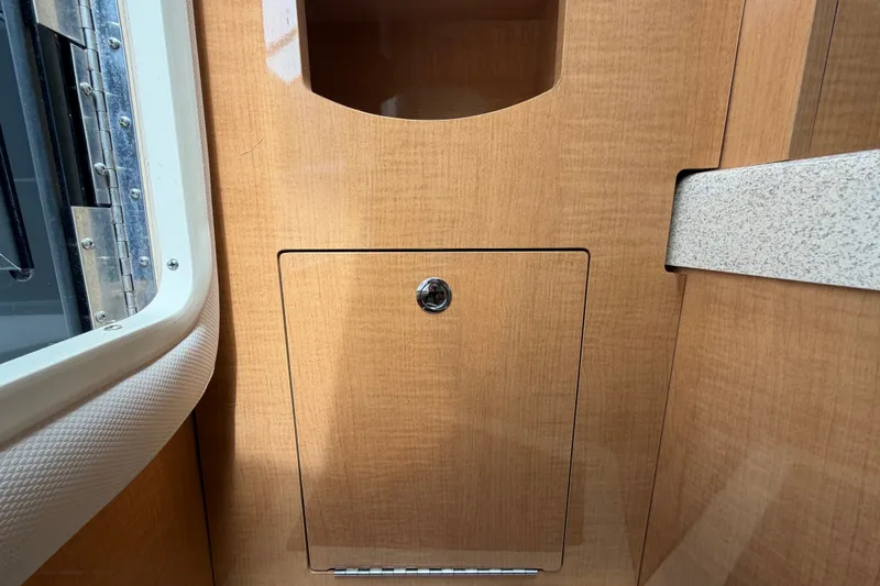 Slide: The Image of Interior cabin detail of 2011 Four Winns V285 boat, featuring wooden cabinetry and a small storage compartment. - 52