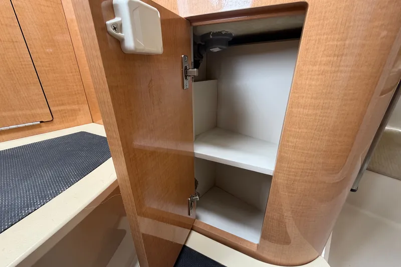 Slide: The Image of Open wooden cabinet with shelves inside a 2011 Four Winns V285 boat interior. - 55