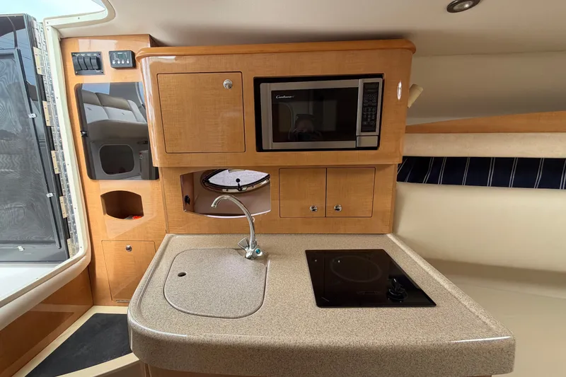 Slide: The Image of 2011 Four Winns V285 boat interior kitchen with microwave, sink, and stove. - 56