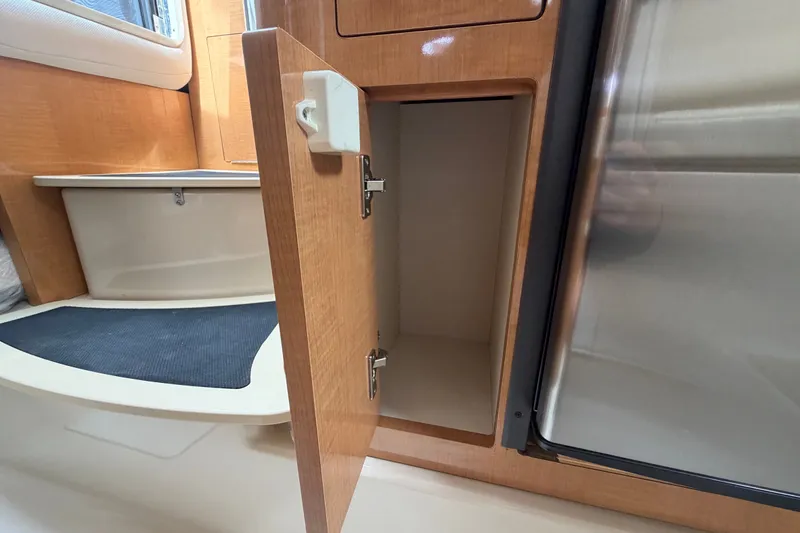 Slide: The Image of Open wooden cabinet in 2011 Four Winns V285 boat interior, showcasing storage space. - 66