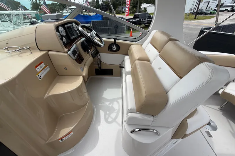 Slide: The Image of 2011 Four Winns V285 boat interior with beige and white seating, steering wheel, and dashboard controls. - 18