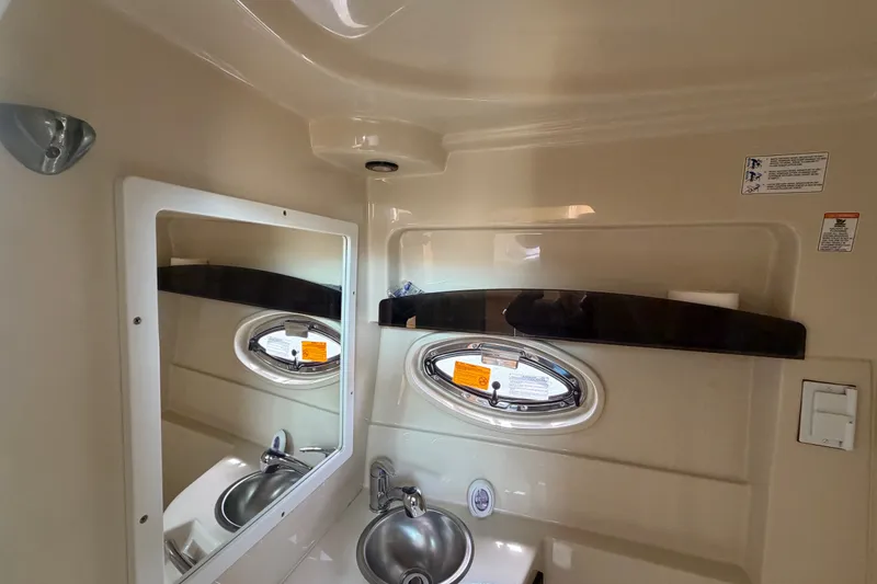 Slide: The Image of 2011 Four Winns V285 boat interior with sink, mirror, and porthole window. - 84