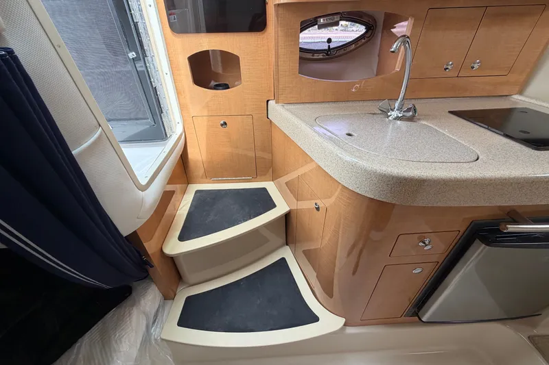 Slide: The Image of Interior of 2011 Four Winns V285 boat featuring compact kitchen and steps. - 46