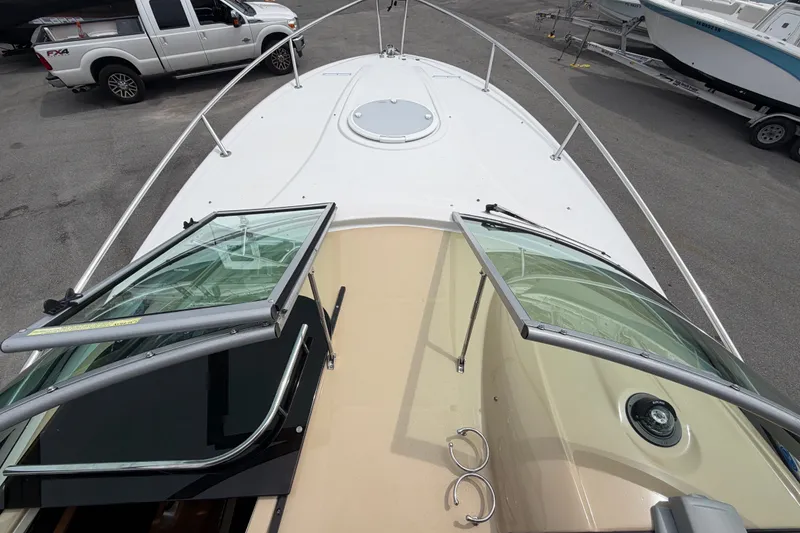 Slide: The Image of 2011 Four Winns V285 boat deck with open windshield, parked near vehicles. - 31