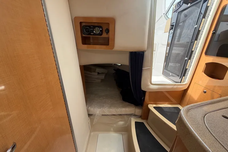 Slide: The Image of Interior cabin of 2011 Four Winns V285 boat, featuring wood accents and cozy sleeping area. - 88
