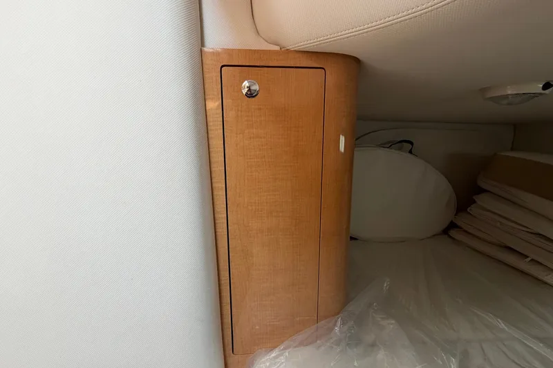 Slide: The Image of Interior cabin storage of 2011 Four Winns V285 boat, featuring wooden cabinet and cushions. - 94