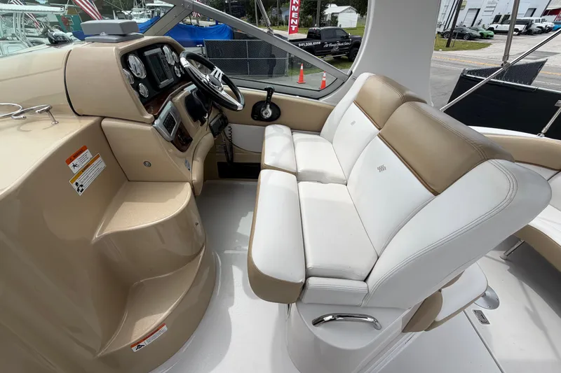 Slide: The Image of 2011 Four Winns V285 boat cockpit with beige and white seating, steering wheel, and dashboard controls. - 17