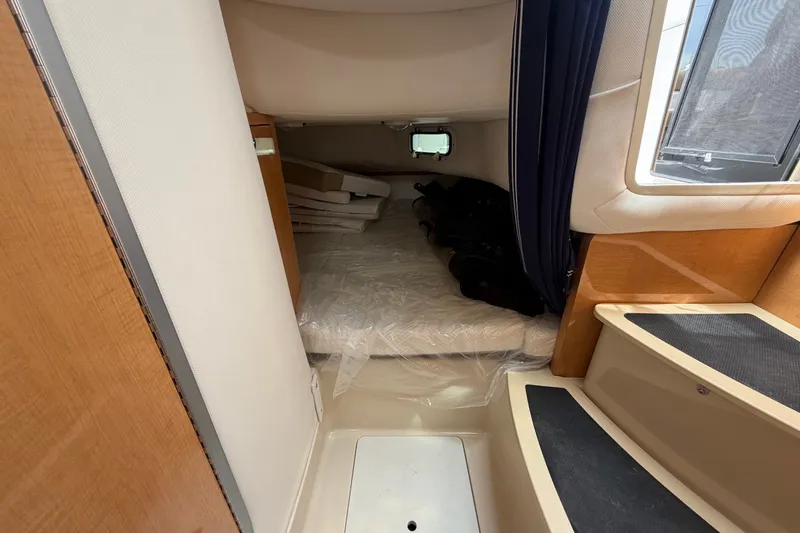 Slide: The Image of Interior cabin of 2011 Four Winns V285 boat, featuring a cozy sleeping area and wooden accents. - 90