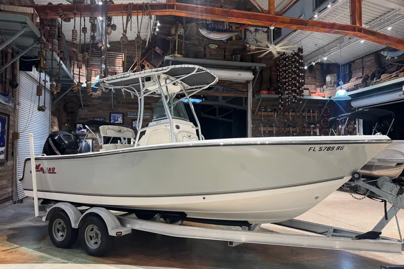 Slide: The Image of 2015 Mako 214 Center Console boat on trailer in a rustic garage setting. - 0