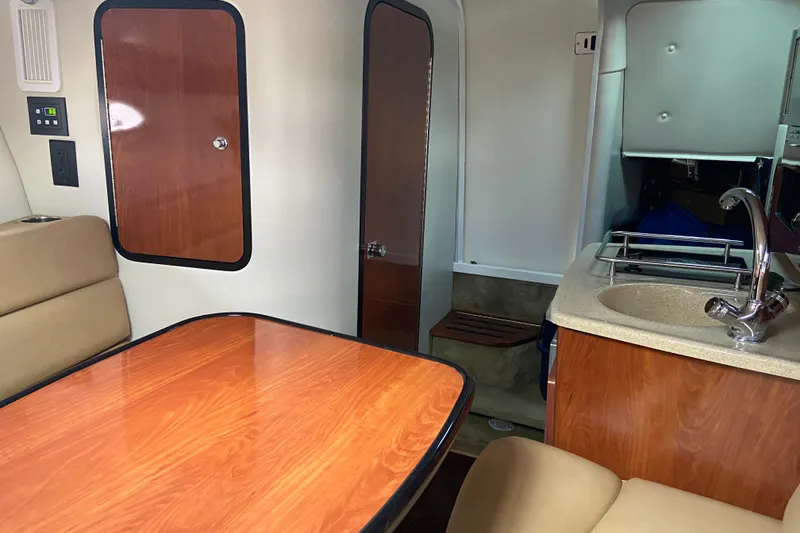 Slide: The Image of Interior of 2012 Crownline 260 CR boat with wood accents and compact kitchenette. - 19