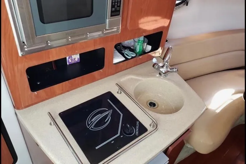 Slide: The Image of 2012 Crownline 260 CR boat interior with kitchenette, featuring sink and microwave. - 15