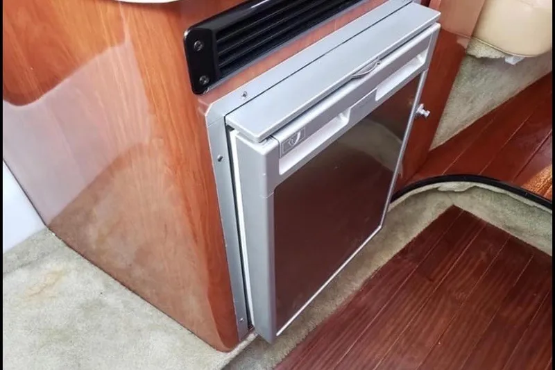 Slide: The Image of Compact refrigerator in 2012 Crownline 260 CR boat interior with wood paneling. - 16