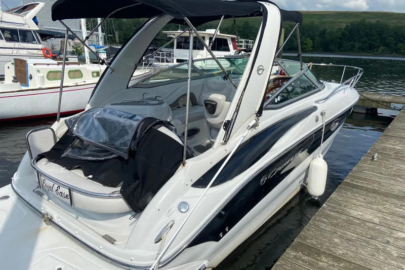 Slide: The Image of 2012 Crownline 260 CR boat docked at marina, featuring sleek design and canopy. - 25