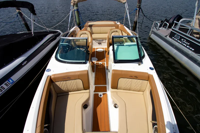 Slide: The Image of A 2015 Sea Ray 220 Sundeck docked. It features beige upholstery and an open deck. - 25