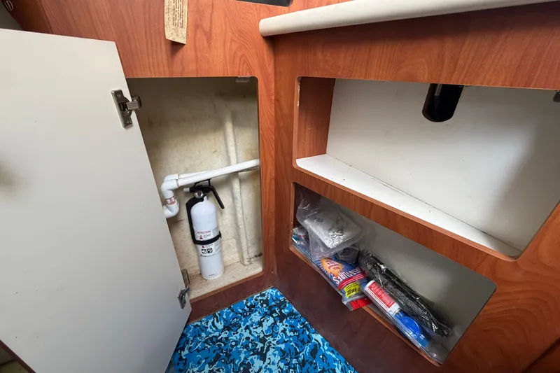 Slide: The Image of 2004 Bayliner 2452 Ciera Express interior storage with fire extinguisher and supplies. - 41