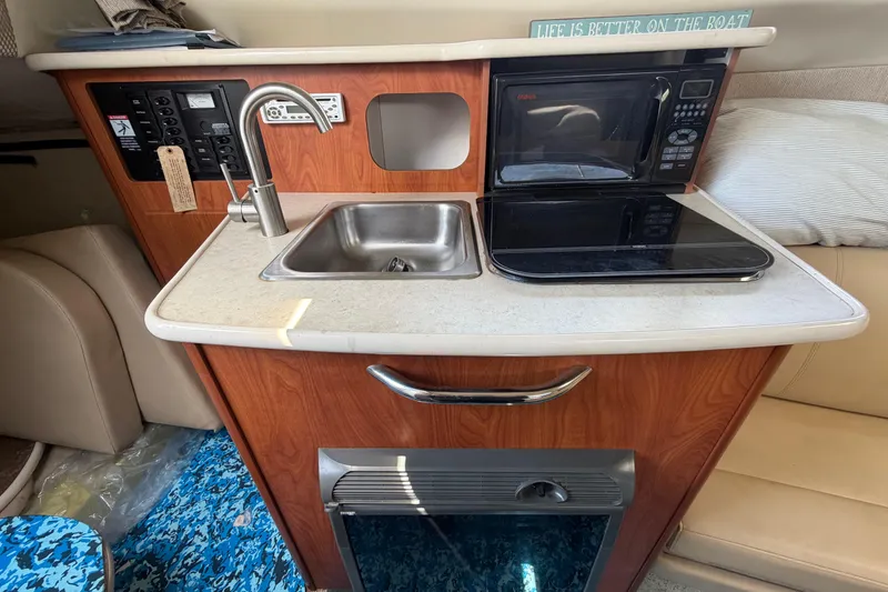 Slide: The Image of 2004 Bayliner 2452 Ciera Express kitchenette with sink, stove, and microwave. - 38