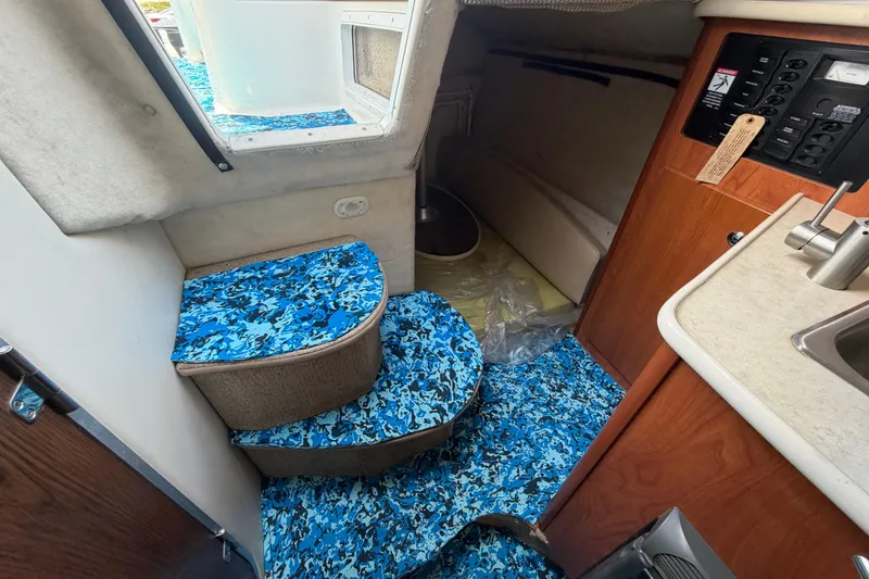 Slide: The Image of Interior of 2004 Bayliner 2452 Ciera Express with blue patterned flooring and compact kitchen area. - 50