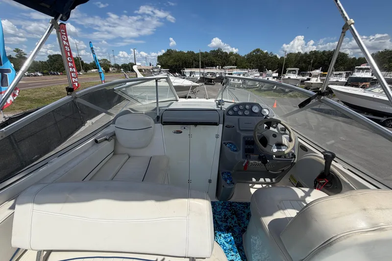 Slide: The Image of 2004 Bayliner 2452 Ciera Express boat interior with steering wheel and seating under clear skies. - 21