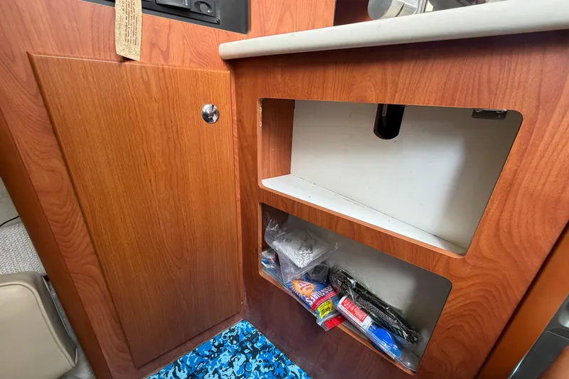 Slide: The Image of 2004 Bayliner 2452 Ciera Express interior cabinet with storage shelves and blue patterned floor. - 40