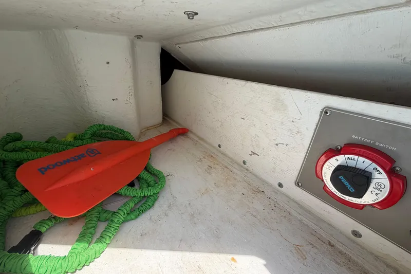 Slide: The Image of Storage compartment of 2004 Bayliner 2452 Ciera Express with paddle, rope, and battery switch. - 20