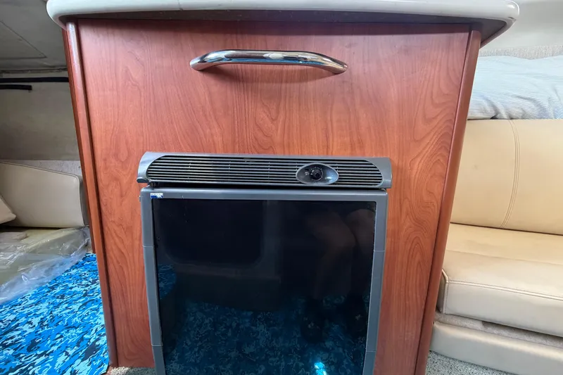 Slide: The Image of 2004 Bayliner 2452 Ciera Express interior with wooden cabinetry and compact refrigerator. - 44