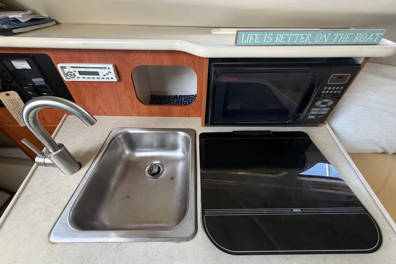 Slide: The Image of 2004 Bayliner 2452 Ciera Express kitchen with sink, stove, microwave, and decor sign. - 43