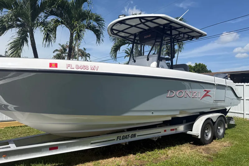 Slide: The Image of 2004 Donzi 29 ZF Open boat on trailer, parked outdoors with palm trees. - 3