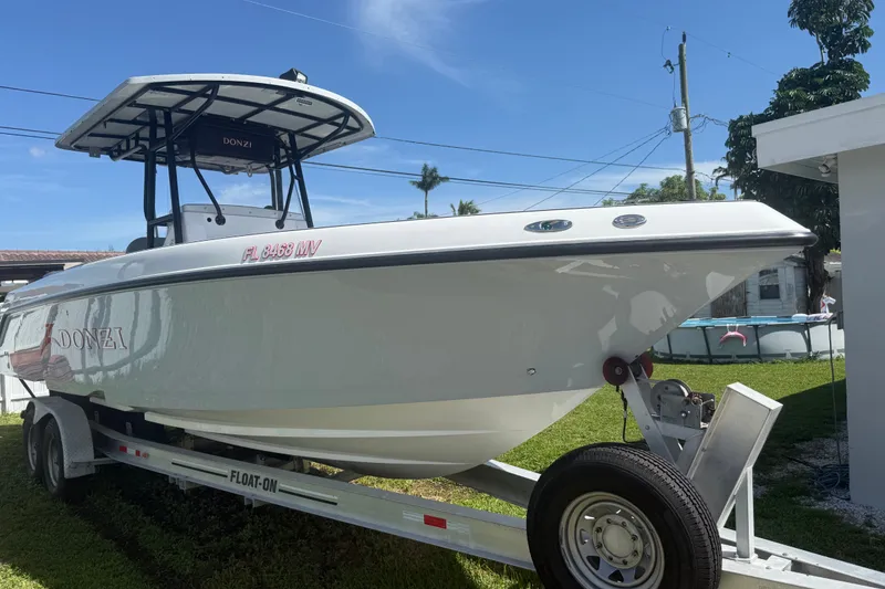 Slide: The Image of 2004 Donzi 29 ZF Open boat on trailer, parked in a grassy yard. - 16