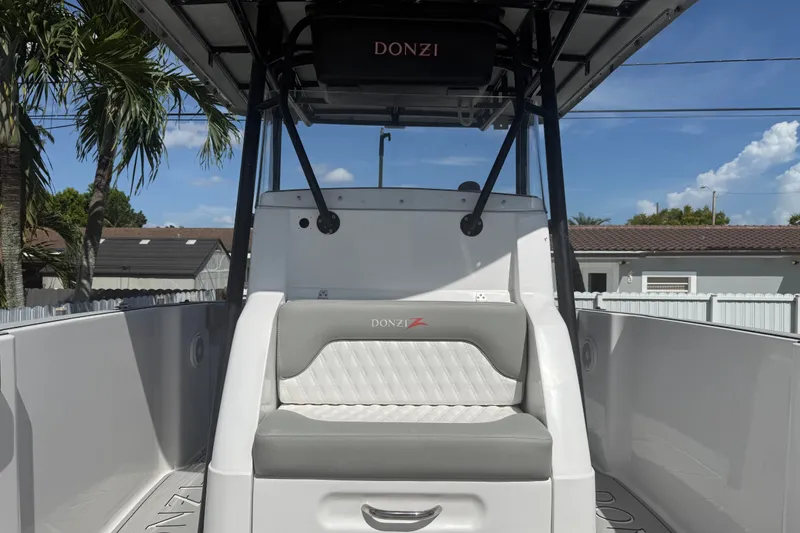 Slide: The Image of 2004 Donzi 29 ZF Open boat interior with seating and canopy, under clear blue sky. - 49