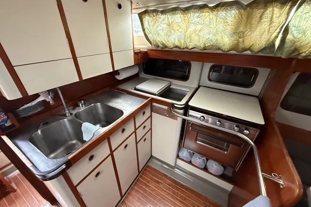 Slide: The Image of 1981 C&C Landfall 38 yacht kitchen with dual sinks, stove, and wooden cabinetry. - 14