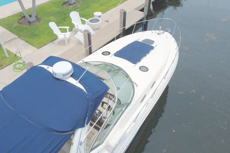 Slide: The Image of 2004 Sea Ray 340 Sundancer yacht docked by a waterfront patio with chairs. - 6
