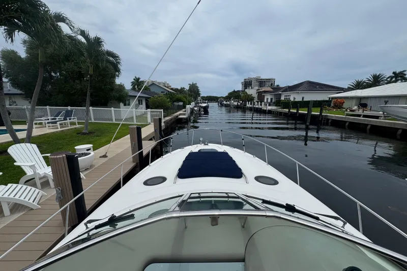 Slide: The Image of 2004 Sea Ray 340 Sundancer docked in a serene canal with palm trees and waterfront homes. - 8