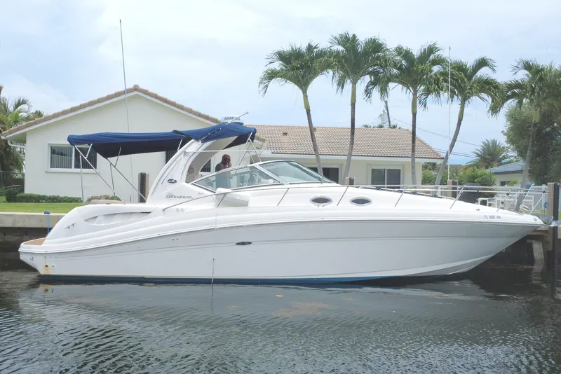 Slide: The Image of 2004 Sea Ray 340 Sundancer yacht docked by a waterfront house with palm trees. - 0