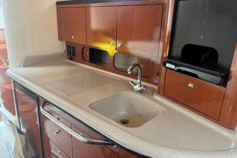 Slide: The Image of 2004 Sea Ray 340 Sundancer galley with sink, wooden cabinets, and countertop. - 25