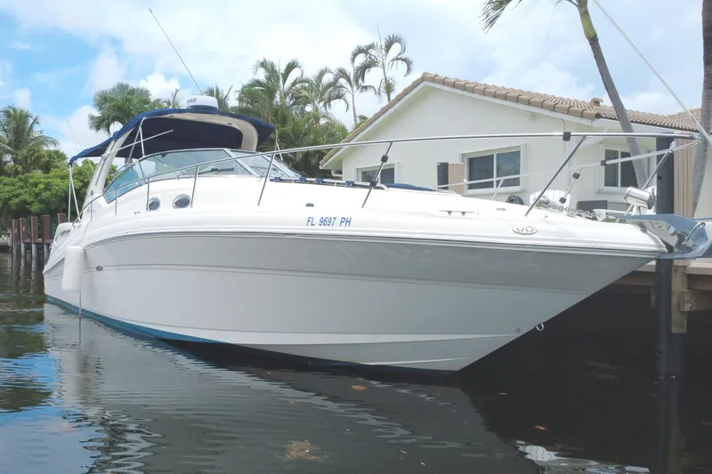Slide: The Image of 2004 Sea Ray 340 Sundancer boat docked near waterfront home, surrounded by palm trees. - 1