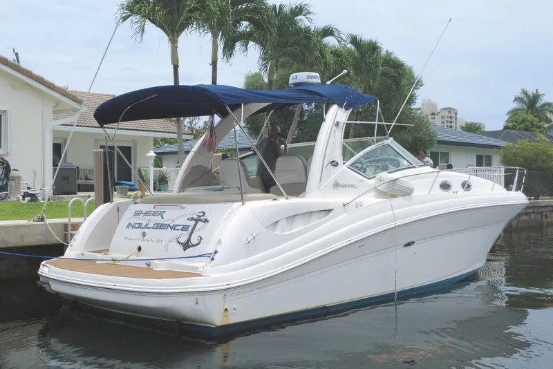 Slide: The Image of 2004 Sea Ray 340 Sundancer yacht docked by a waterfront home with palm trees. - 2
