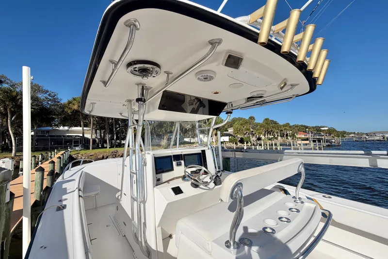 Slide: The Image of 2004 Venture 34 Cuddy boat helm with fishing rod holders, docked by the water. - 24