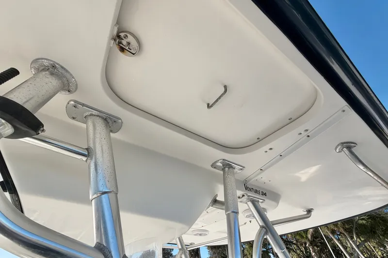 Slide: The Image of 2004 Venture 34 Cuddy boat's T-top structure with rod holders and hatch. - 27
