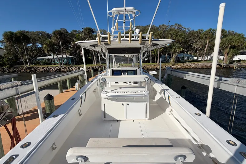 Slide: The Image of 2004 Venture 34 Cuddy boat docked, featuring spacious deck and fishing rod holders. - 11