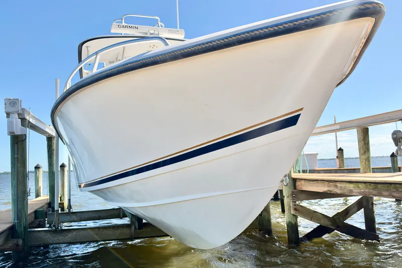Slide: The Image of 2004 Venture 34 Cuddy boat docked, showcasing sleek hull design and Garmin equipment. - 1
