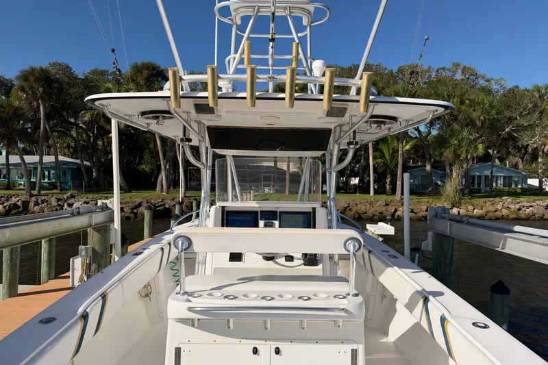 Slide: The Image of 2004 Venture 34 Cuddy boat docked, featuring helm and fishing rod holders. - 12