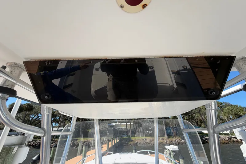 Slide: The Image of 2004 Venture 34 Cuddy boat console with reflection, docked near trees and water. - 97