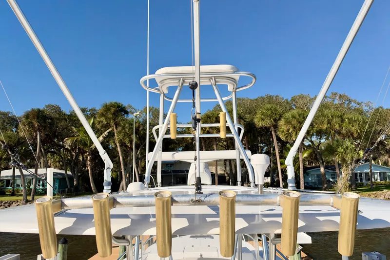 Slide: The Image of 2004 Venture 34 Cuddy boat with fishing rod holders, docked near palm trees. - 15