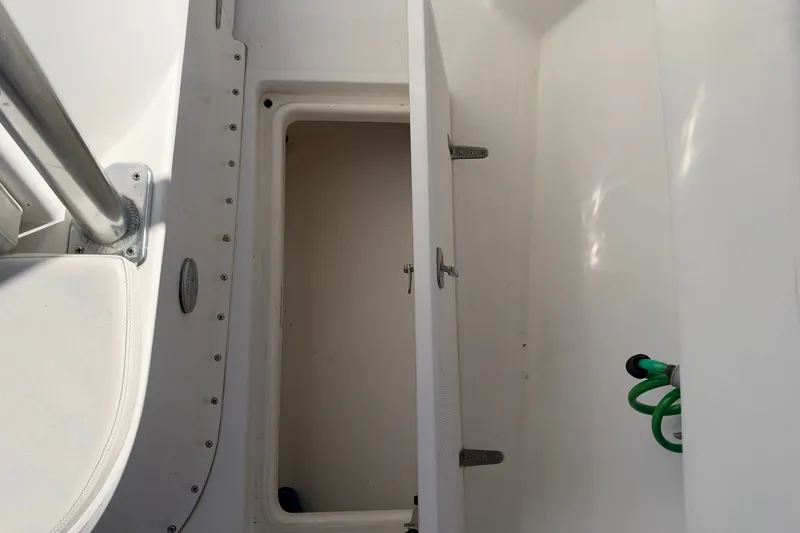 Slide: The Image of 2004 Venture 34 Cuddy boat interior storage compartment with green hose. - 62