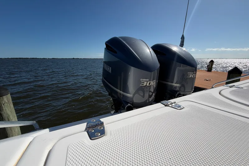 Slide: The Image of Twin Yamaha 300 engines on a 2004 Venture 34 Cuddy boat by the water. - 84