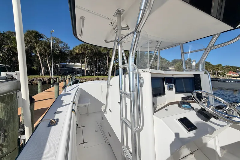 Slide: The Image of 2004 Venture 34 Cuddy boat with modern cockpit and steering, docked by a scenic waterfront. - 37