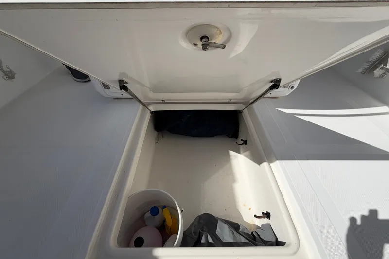 Slide: The Image of Open storage compartment on a 2004 Venture 34 Cuddy boat with cleaning supplies. - 105